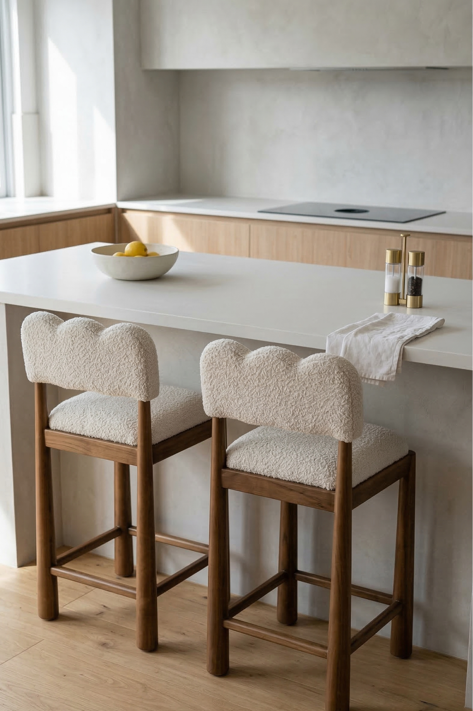 Two wooden bar stools with white cushioned seats in a modern kitchen.