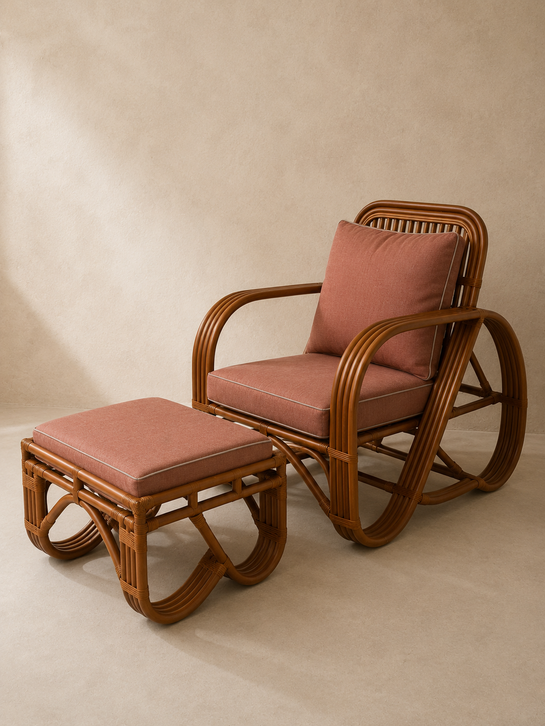 A rattan armchair with a matching ottoman and back cushion, featuring warm brown woven frames and dusty rose cushions, set against a textured beige wall.