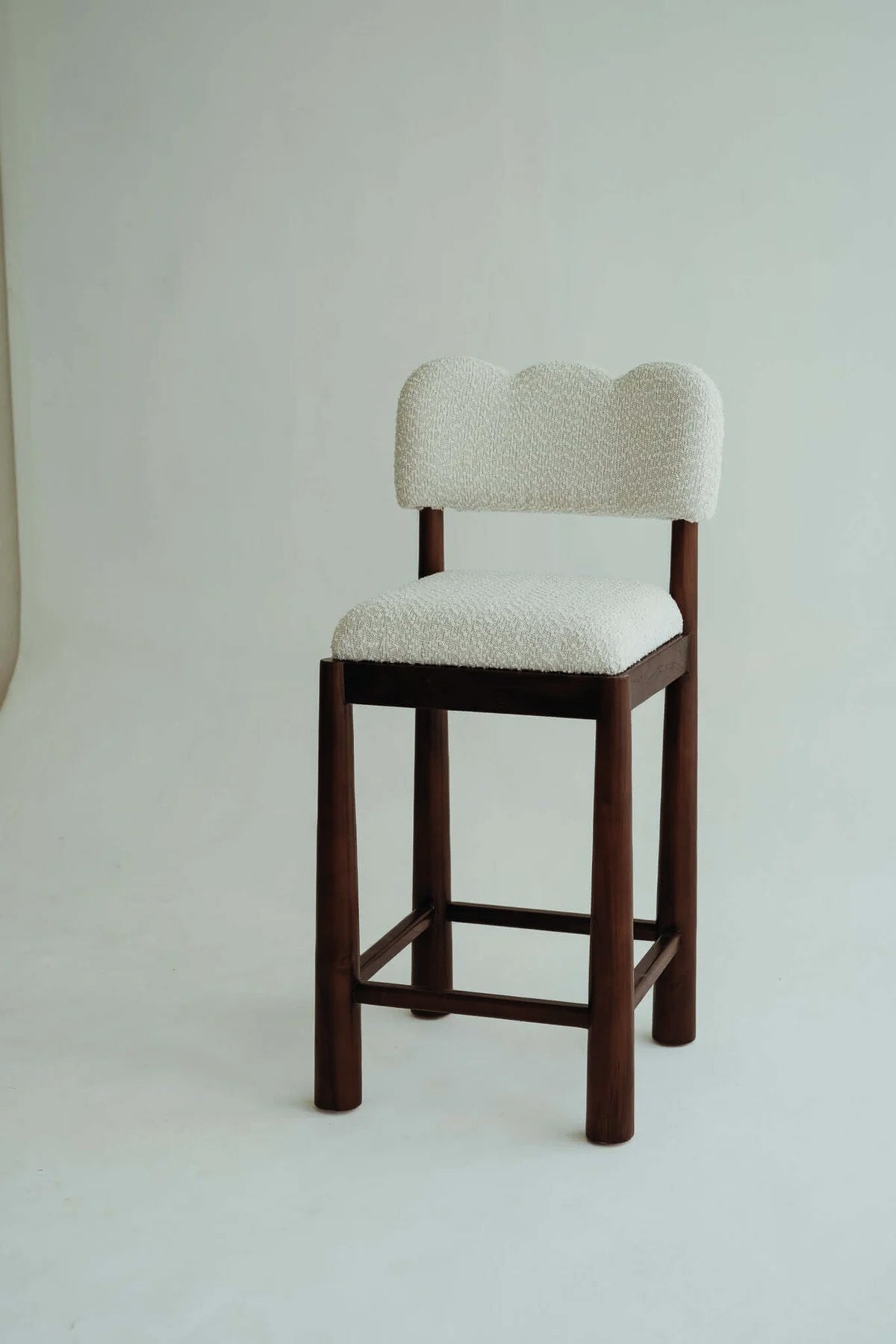 Wavy bar stool chair made of teak wood with a bouclé fabric seat.