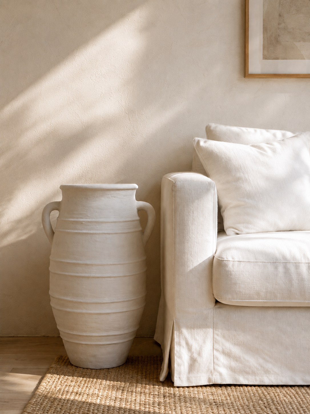 WHITE POT WITH HANDLES ON FLOOR NEXT TO WHITE LINEN COUCH SOFA