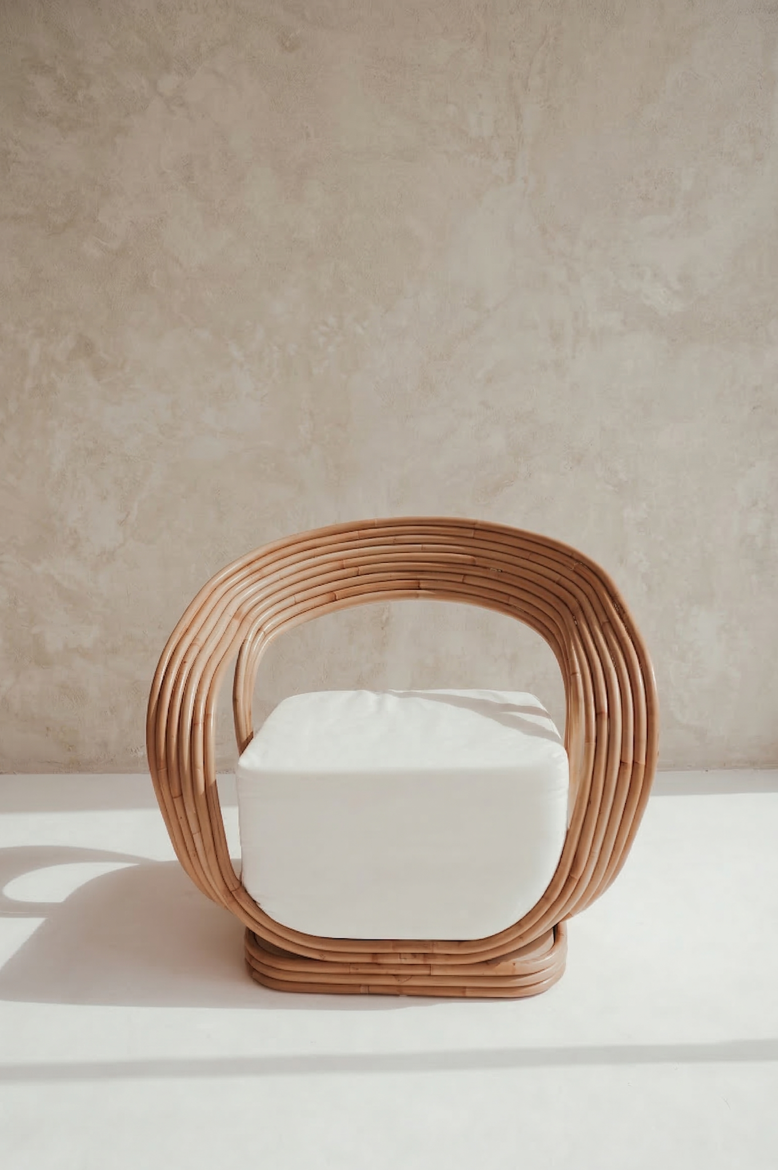 Woven chair with a white cushion on a neutral background